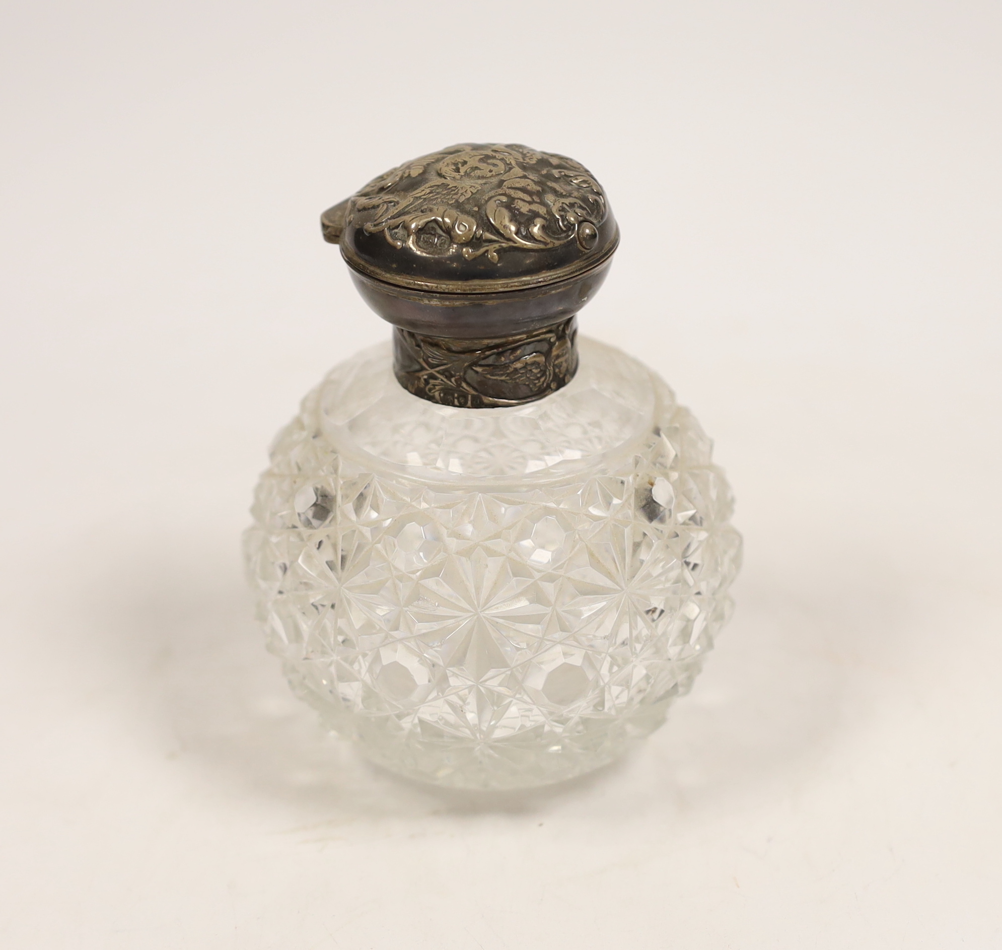 A late Victorian repousse silver mounted cut glass scent bottle, with Reynold's Angels decoration, William Comyns, London, 1896, 13cm.